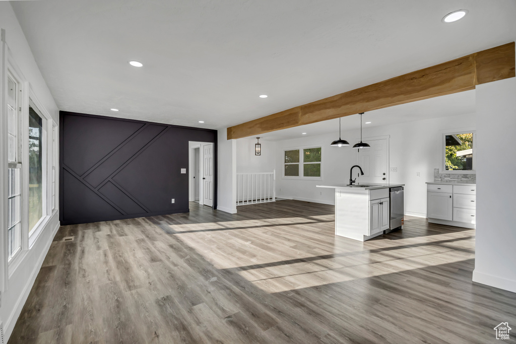 Unfurnished living room with recessed lighting, wood finished floors, and beamed ceiling