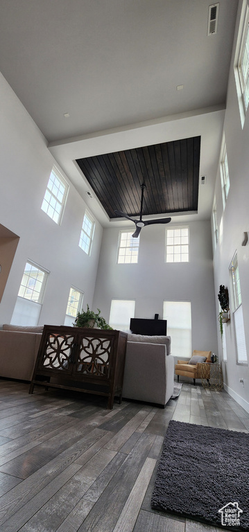 Living area featuring a towering ceiling, plenty of natural light, ceiling fan, and hardwood / wood-style flooring