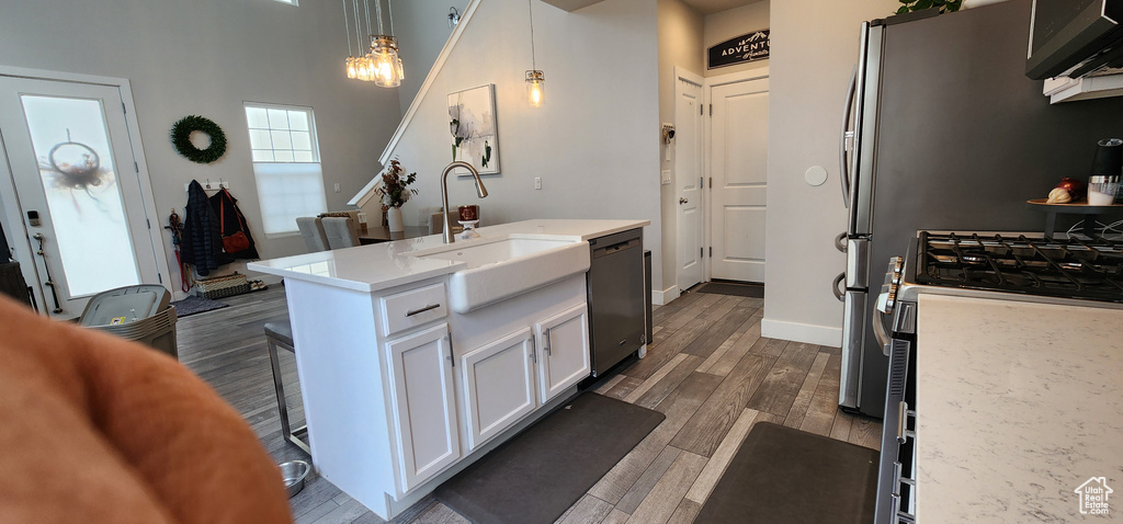 Kitchen featuring stainless steel appliances, white cabinets, dark wood finished floors, hanging light fixtures, and a chandelier