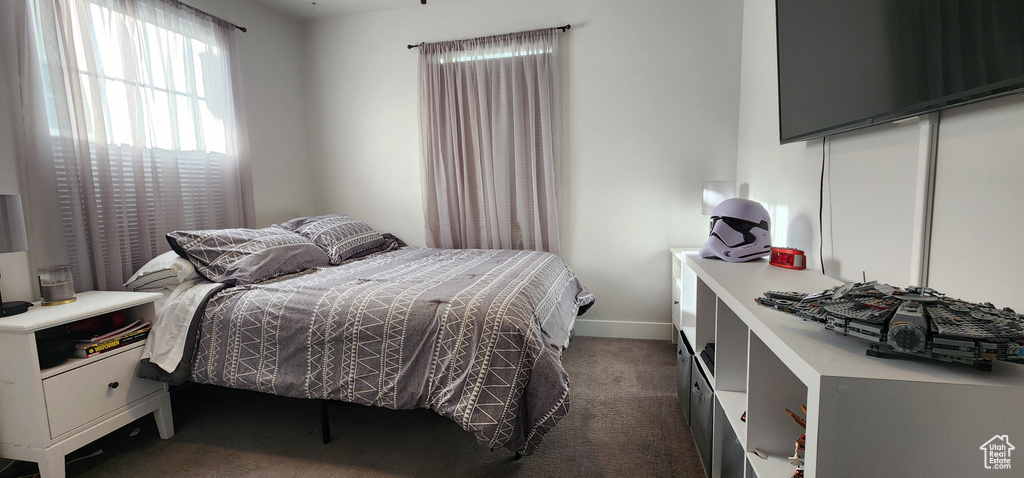 Bedroom featuring dark carpet and baseboards