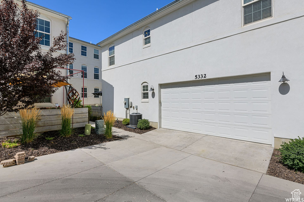 View of side of property featuring stucco siding, concrete driveway, and an attached garage