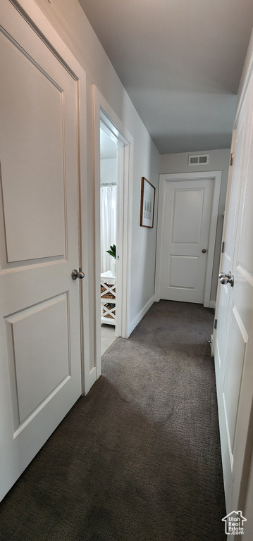 Hall featuring dark carpet and baseboards