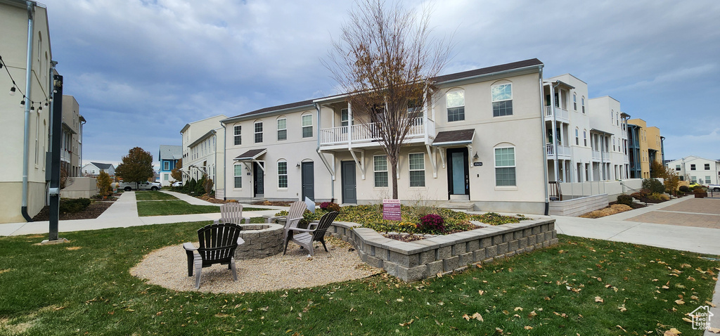 View of front facade featuring a residential view, an outdoor fire pit, a front lawn, and stucco siding
