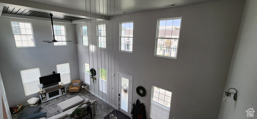 Living room featuring wood finished floors, a towering ceiling, and ceiling fan