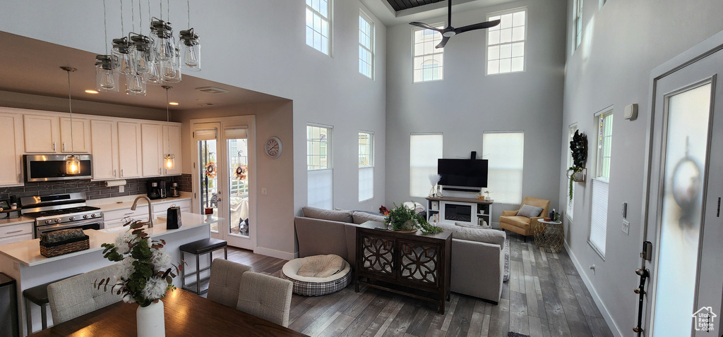 Living room featuring a towering ceiling, dark wood-style floors, and a ceiling fan