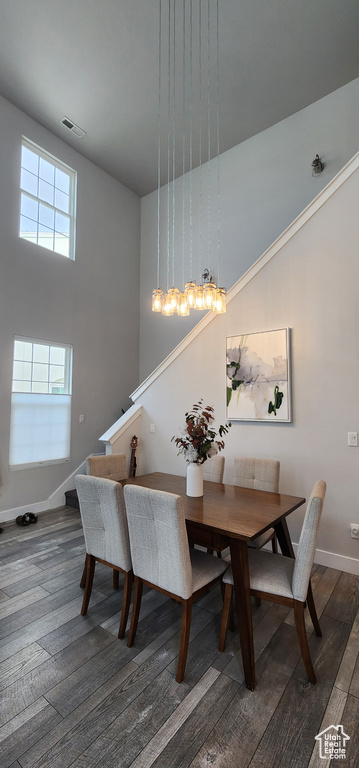 Dining area featuring wood finished floors, stairs, and a high ceiling