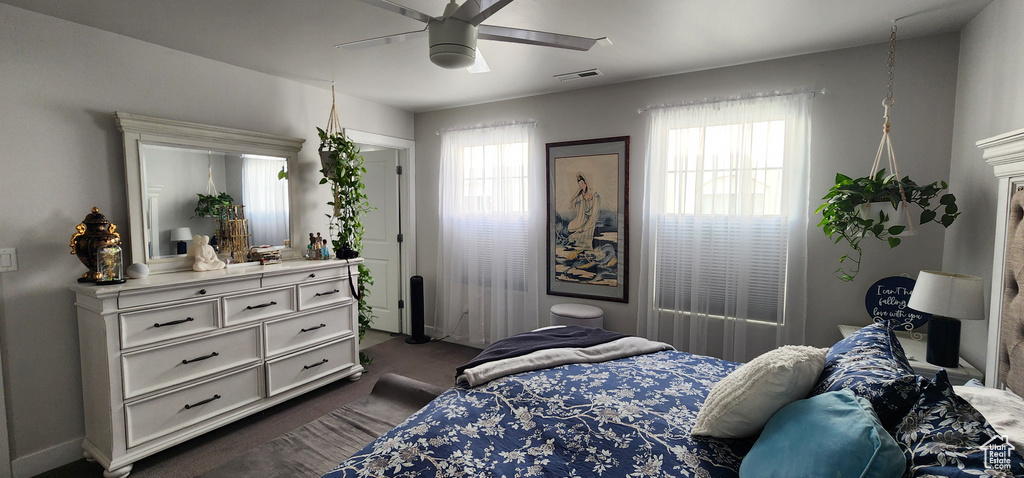 Bedroom with multiple windows, dark carpet, and a ceiling fan