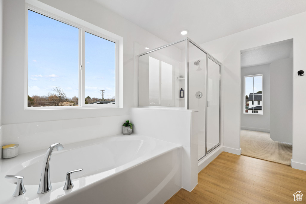 Full bath featuring a stall shower, a garden tub, and wood finished floors