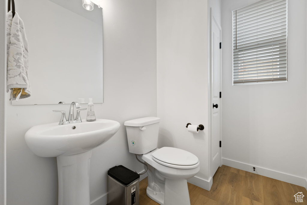 Half bathroom with wood finished floors and toilet