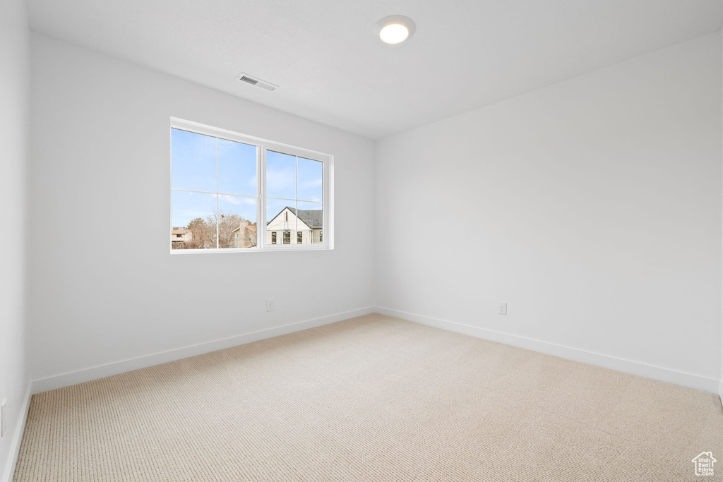 Spare room featuring light colored carpet and baseboards