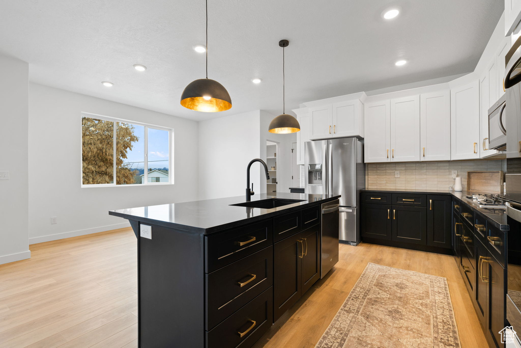 Kitchen featuring dark cabinetry, stainless steel appliances, dark countertops, white cabinets, and recessed lighting