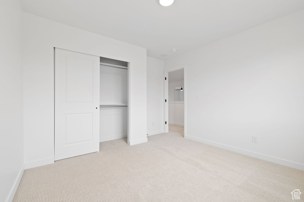 Unfurnished bedroom featuring light colored carpet and a closet