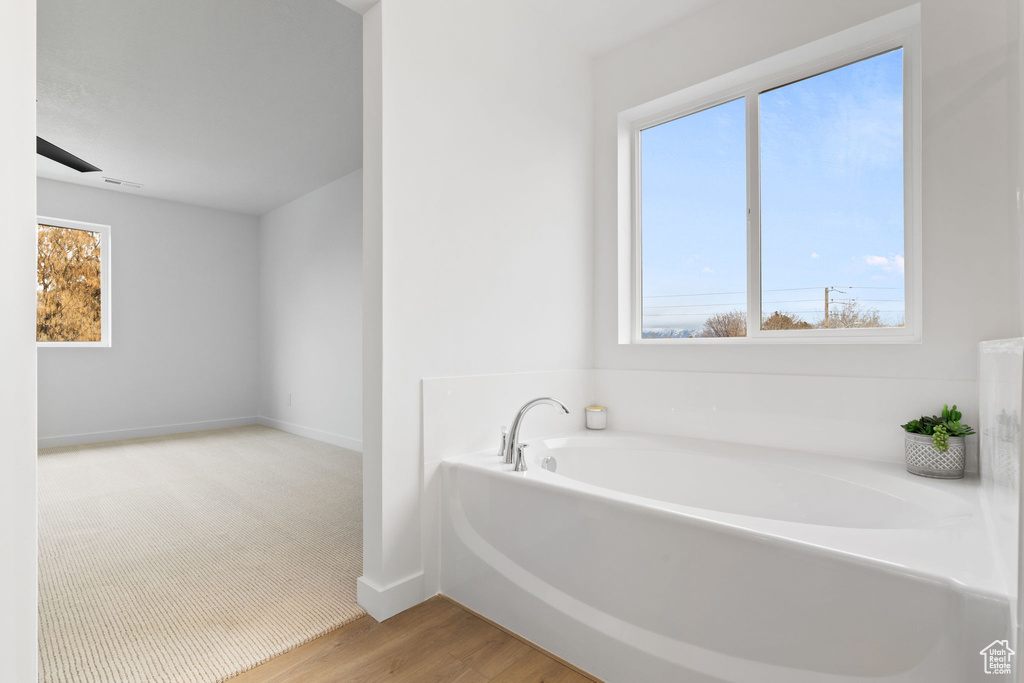 Bathroom featuring a bath and wood finished floors
