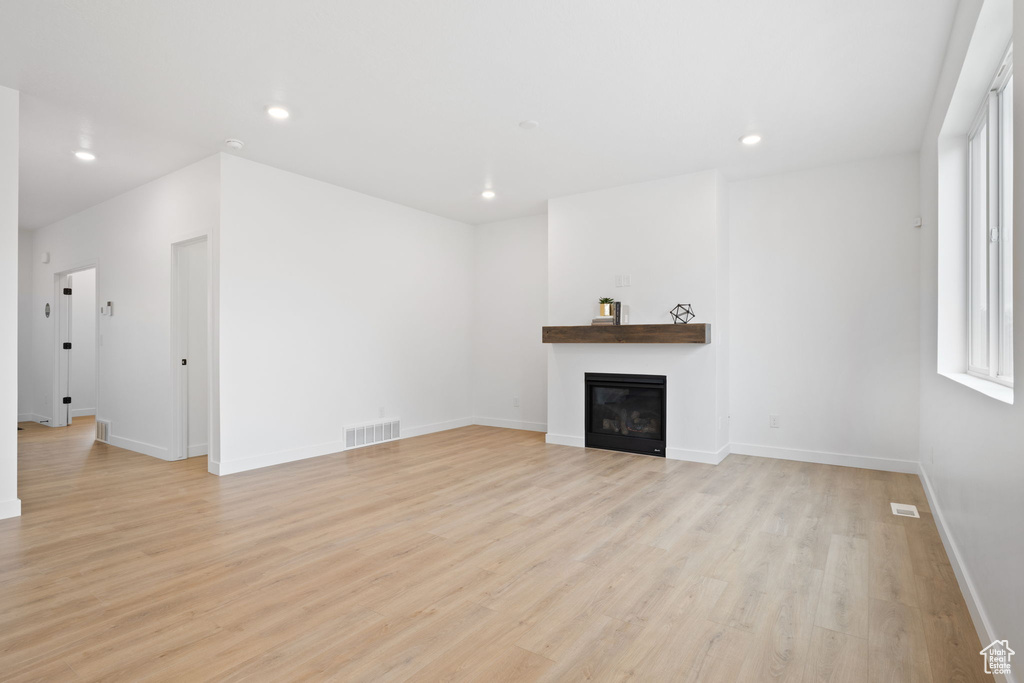 Unfurnished living room featuring light wood-style floors, a glass covered fireplace, and recessed lighting