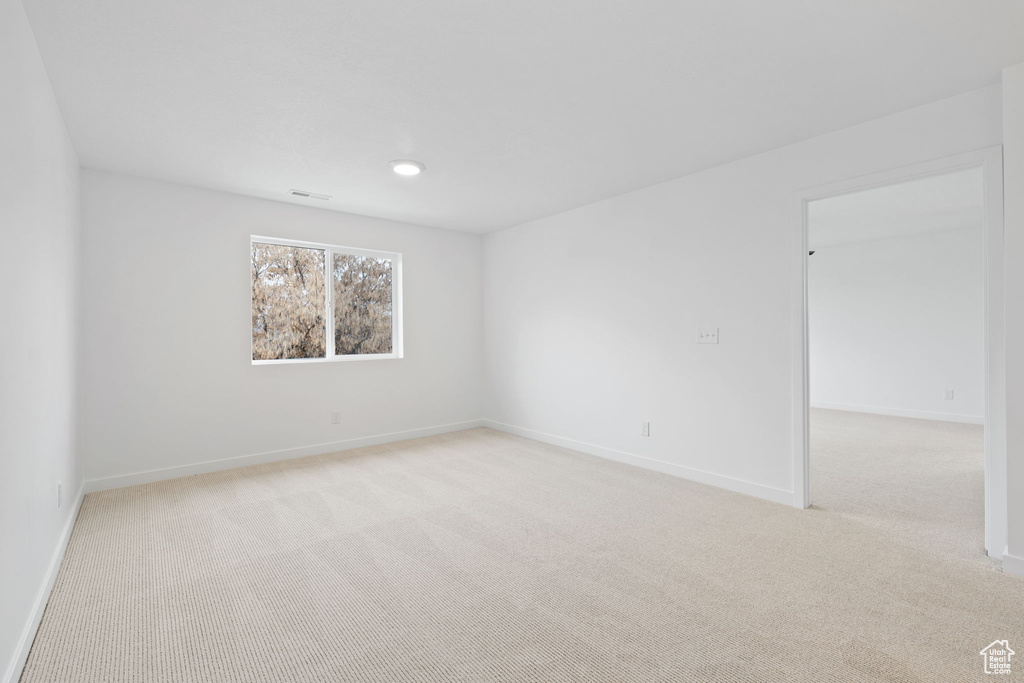 Empty room featuring light carpet and baseboards