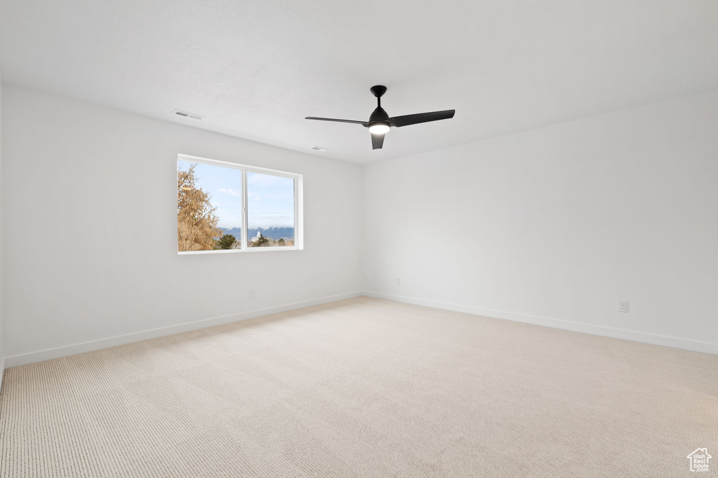 Spare room with a ceiling fan and light carpet