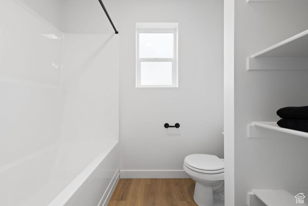 Full bathroom featuring wood finished floors and washtub / shower combination