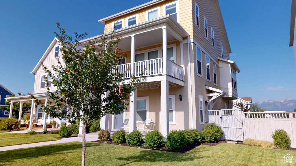View of front of property with a gate and a balcony