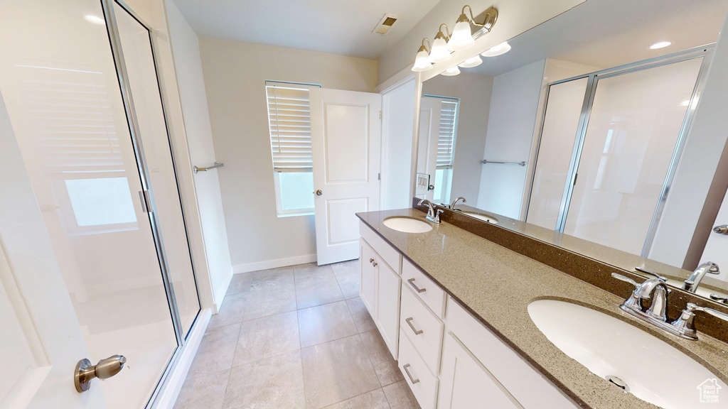 Full bath featuring a stall shower, double vanity, tile patterned floors, and plenty of natural light