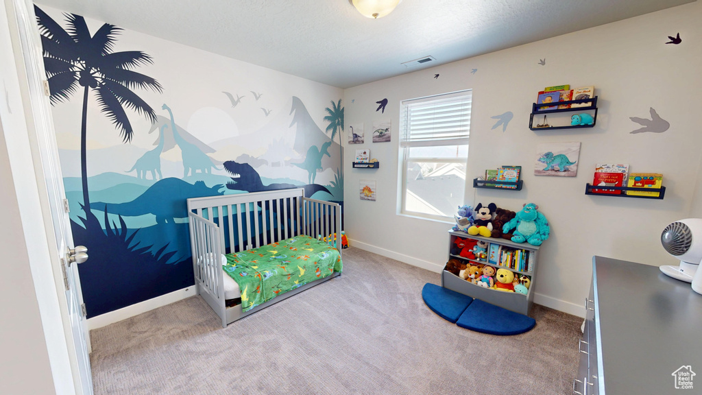 Carpeted bedroom featuring baseboards and a nursery area