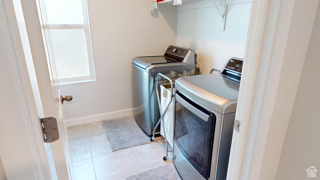 Laundry area with independent washer and dryer and light tile patterned floors