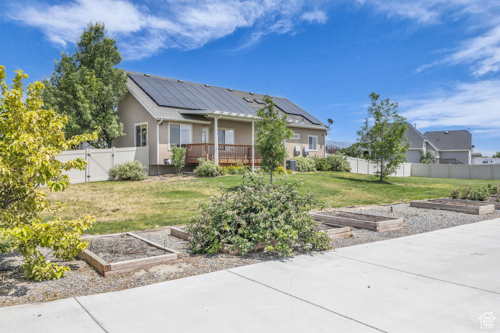 Rear view of property featuring a garden, a gate, solar panels, and a wooden deck