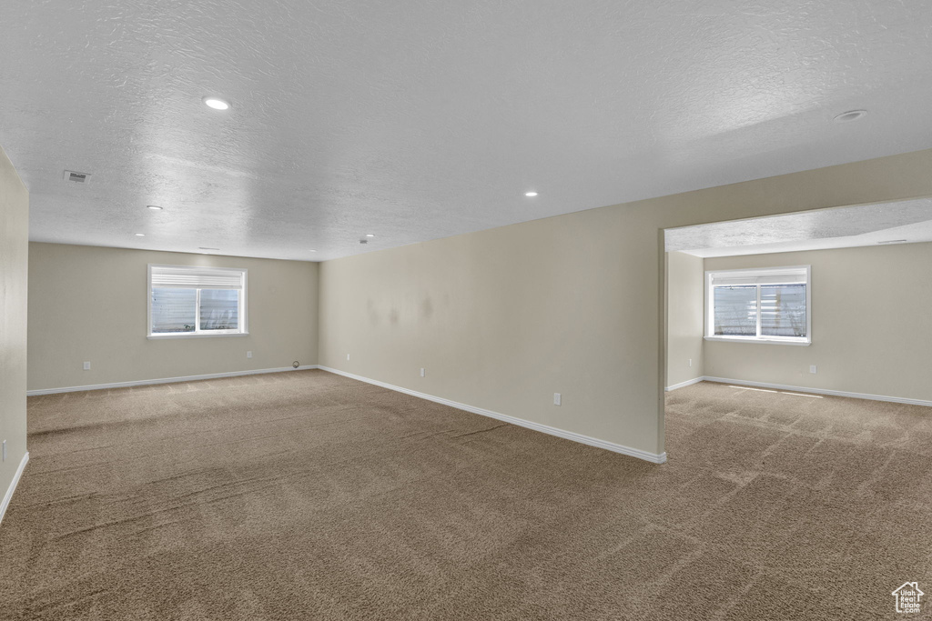 Empty room with a textured ceiling, carpet floors, and recessed lighting