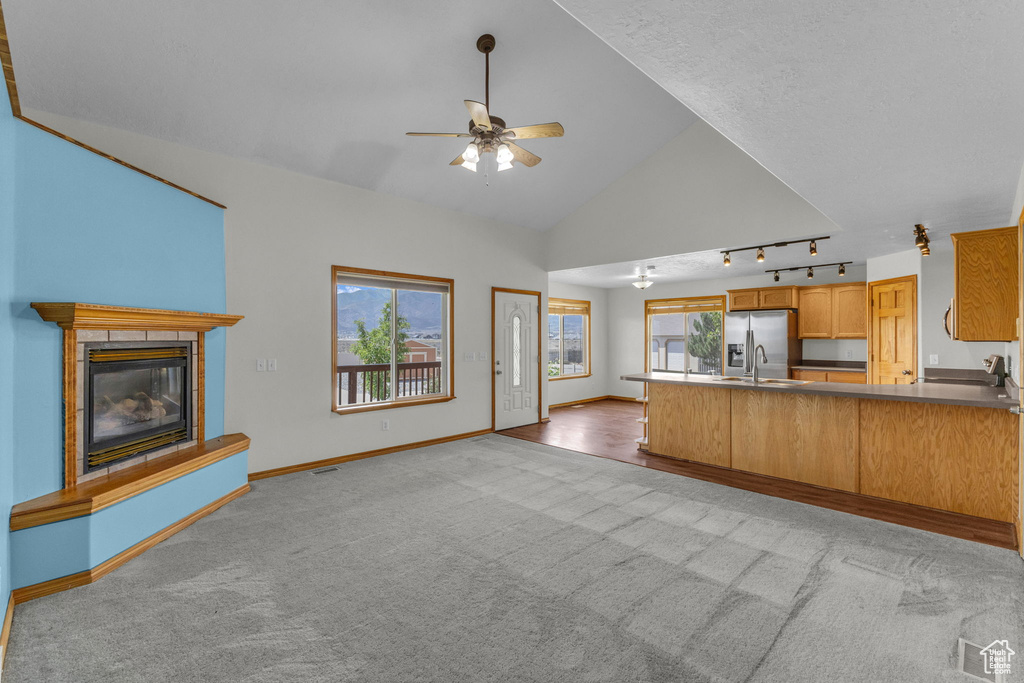 Kitchen with ceiling fan, lofted ceiling, light colored carpet, stainless steel refrigerator with ice dispenser, and a peninsula