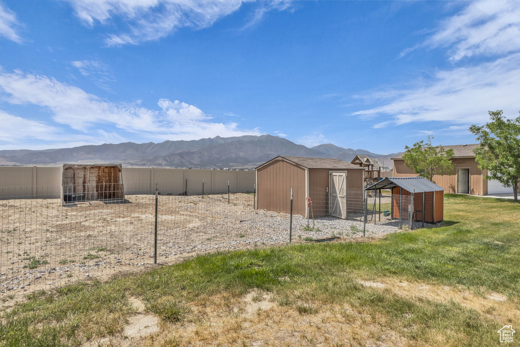 Back of property featuring exterior structure, a mountain view, and a storage unit