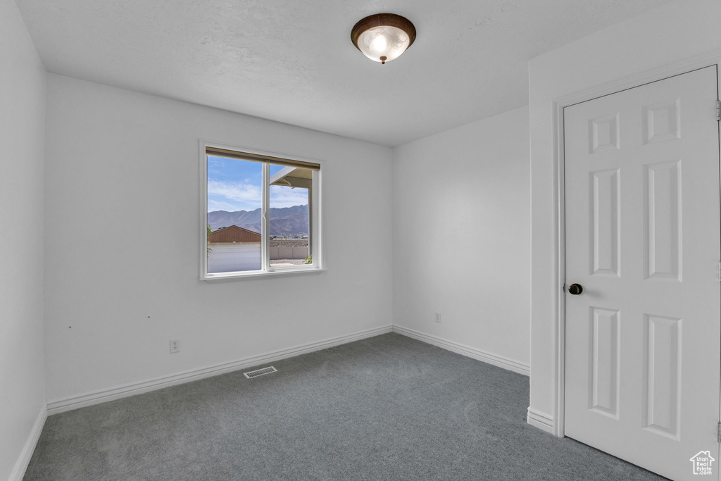 Spare room with dark carpet and baseboards
