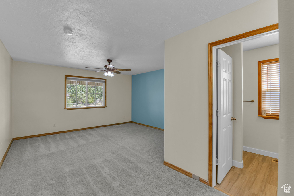 Empty room featuring a ceiling fan and a textured ceiling