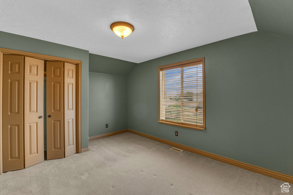 Unfurnished bedroom featuring lofted ceiling, carpet, and a closet