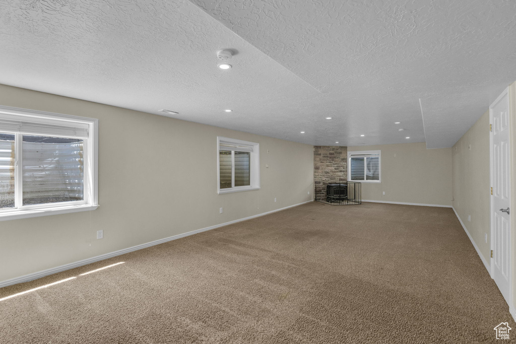 Unfurnished living room with carpet floors, a textured ceiling, a fireplace, and recessed lighting