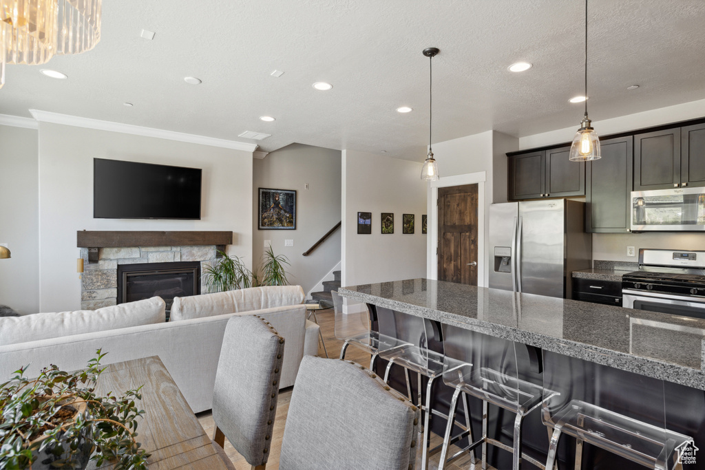 Kitchen featuring appliances with stainless steel finishes, a breakfast bar area, recessed lighting, ornamental molding, and a fireplace