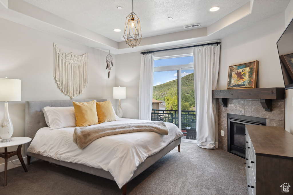 Carpeted bedroom with access to outside, a fireplace, recessed lighting, a raised ceiling, and a textured ceiling