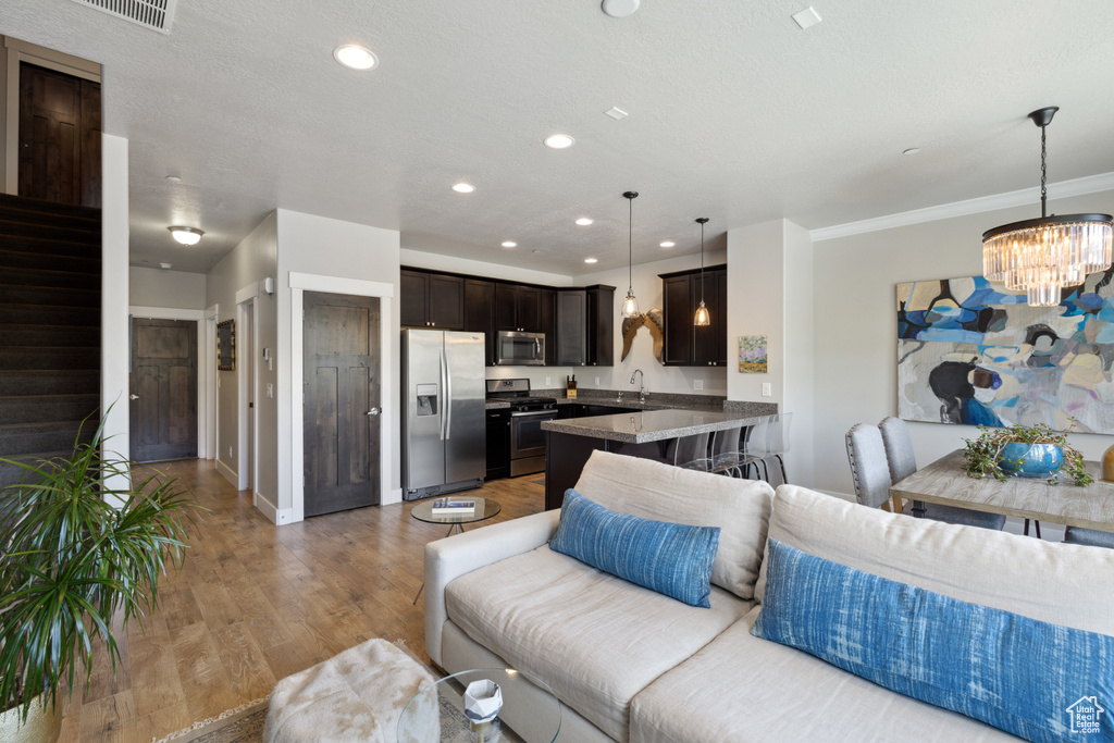 Living area featuring a chandelier, wood finished floors, recessed lighting, and crown molding