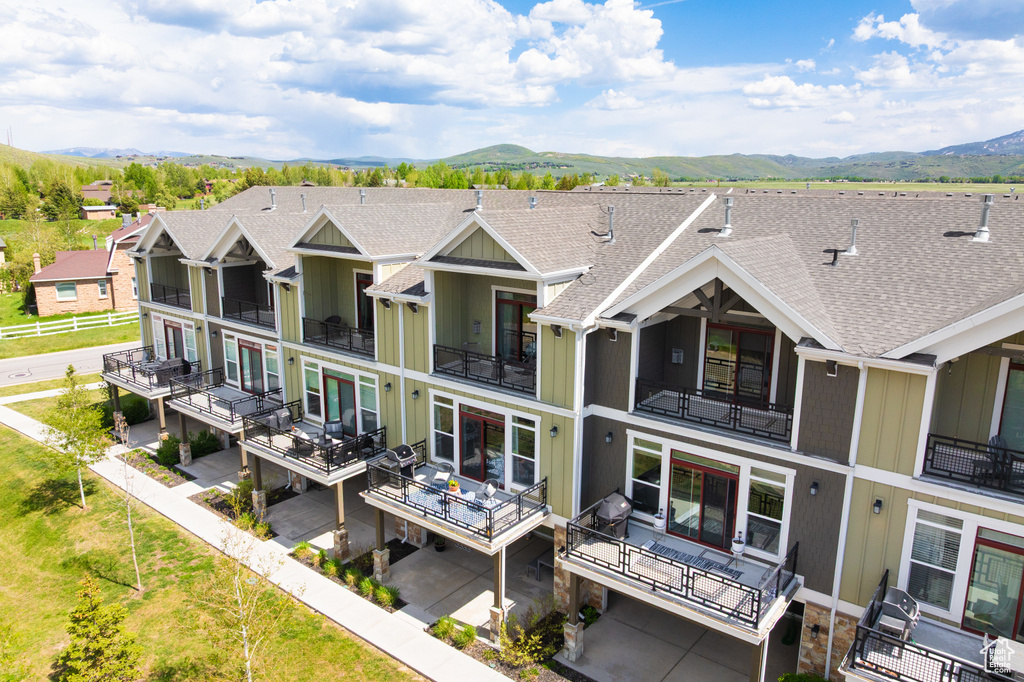 Back of property with a mountain view, a shingled roof, and a balcony