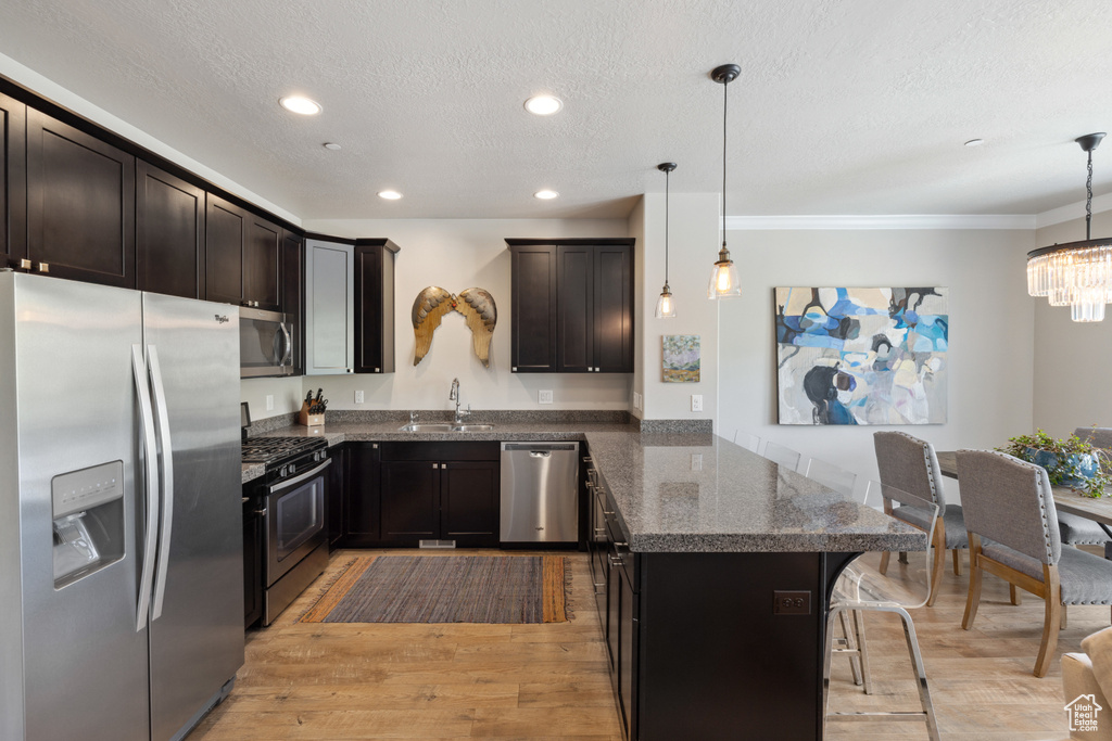 Kitchen with stainless steel appliances, a peninsula, a kitchen bar, crown molding, and a chandelier