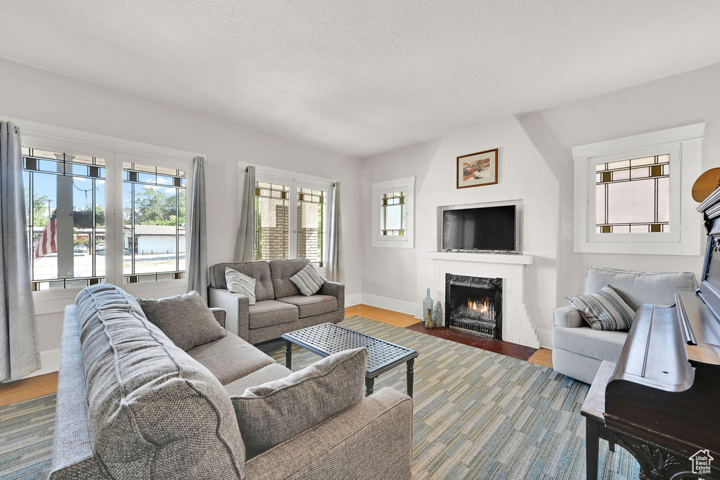 Living room with a large fireplace, plenty of natural light, and wood finished floors
