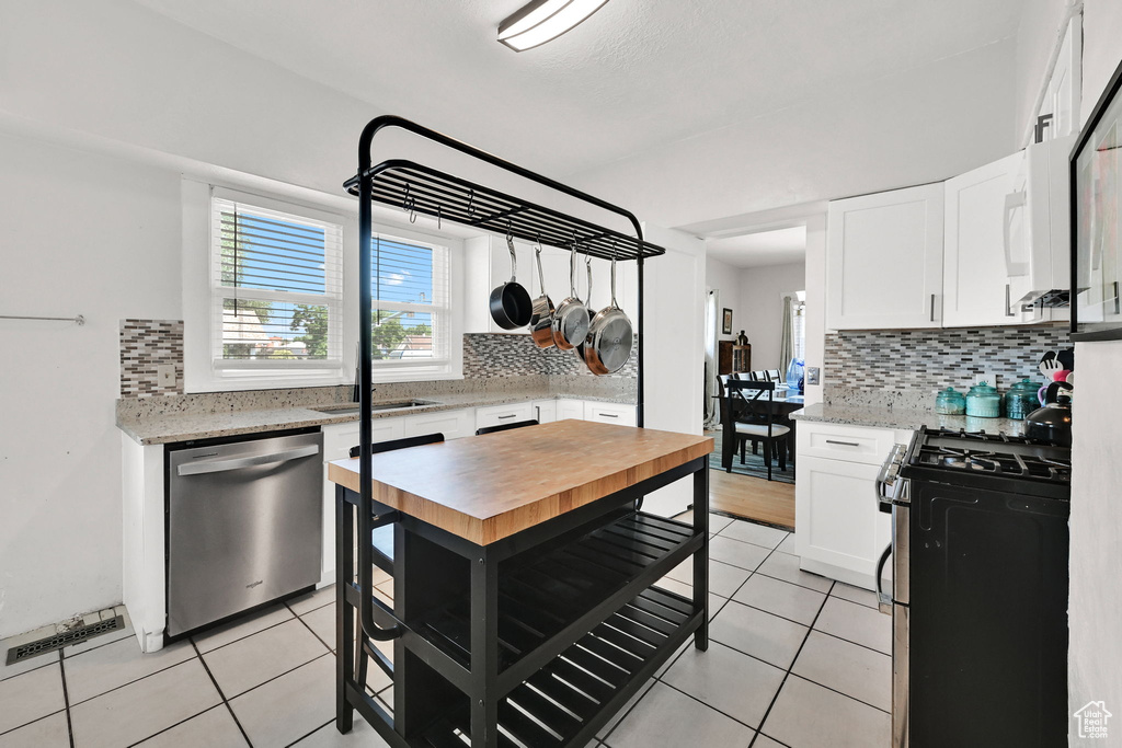Kitchen with appliances with stainless steel finishes, decorative backsplash, and light tile patterned floors