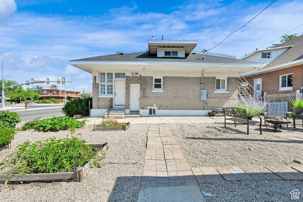 Back of house with an outdoor fire pit, brick siding, a vegetable garden, and a patio area