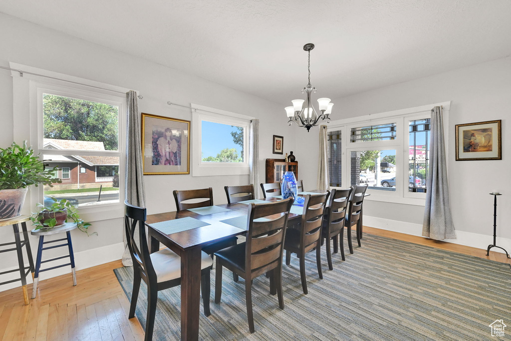 Dining space featuring healthy amount of natural light, light wood-type flooring, and a chandelier
