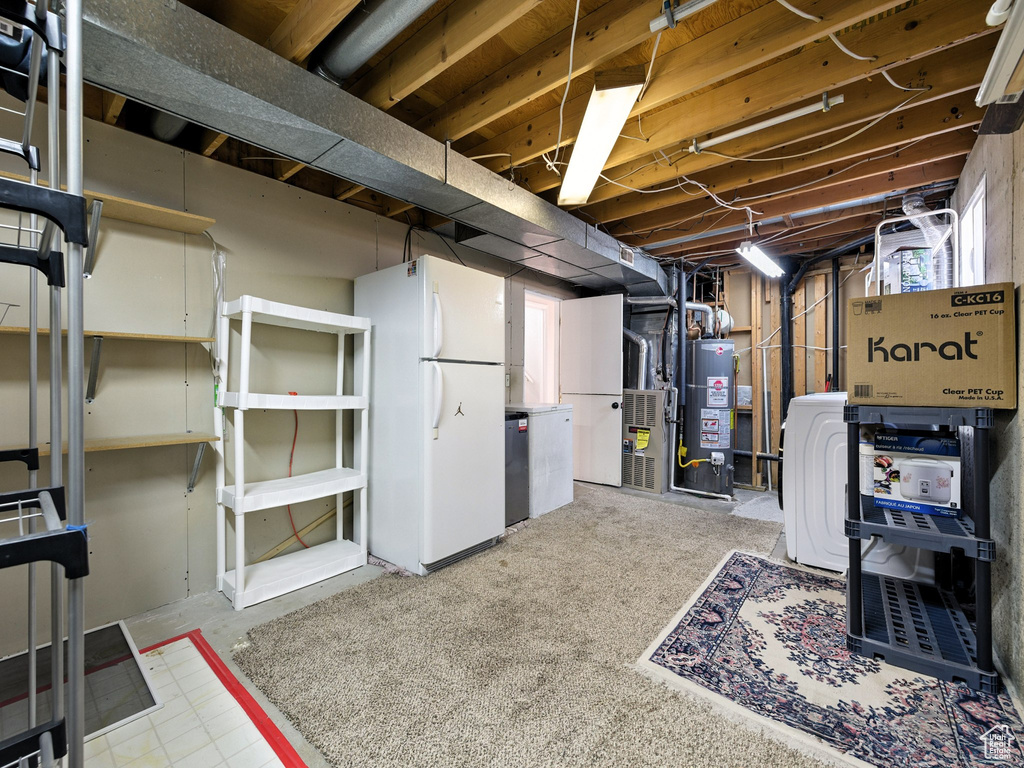 Below grade area with freestanding refrigerator, water heater, and heating unit