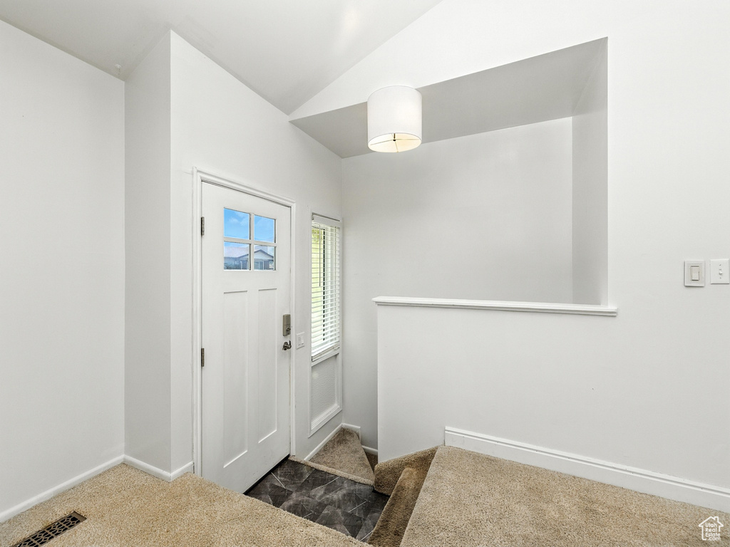 Foyer featuring carpet and vaulted ceiling