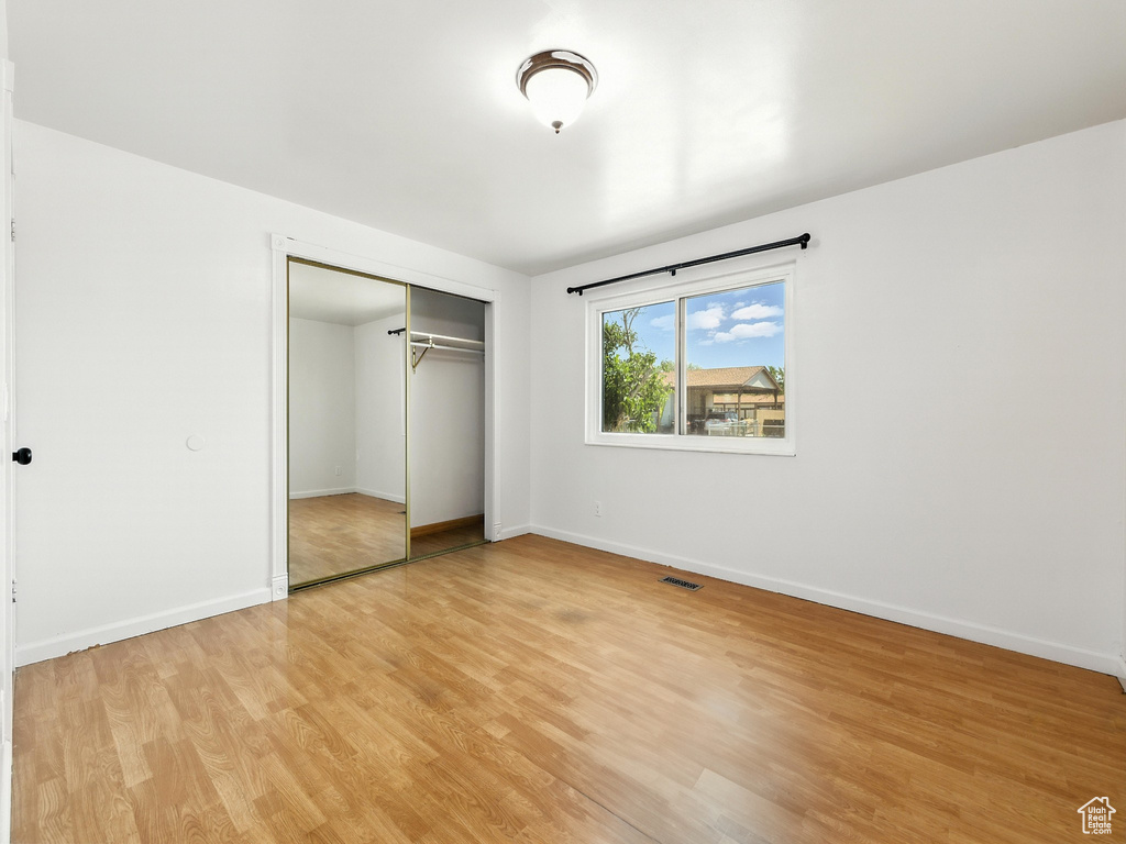 Unfurnished bedroom featuring light wood-style floors and a closet