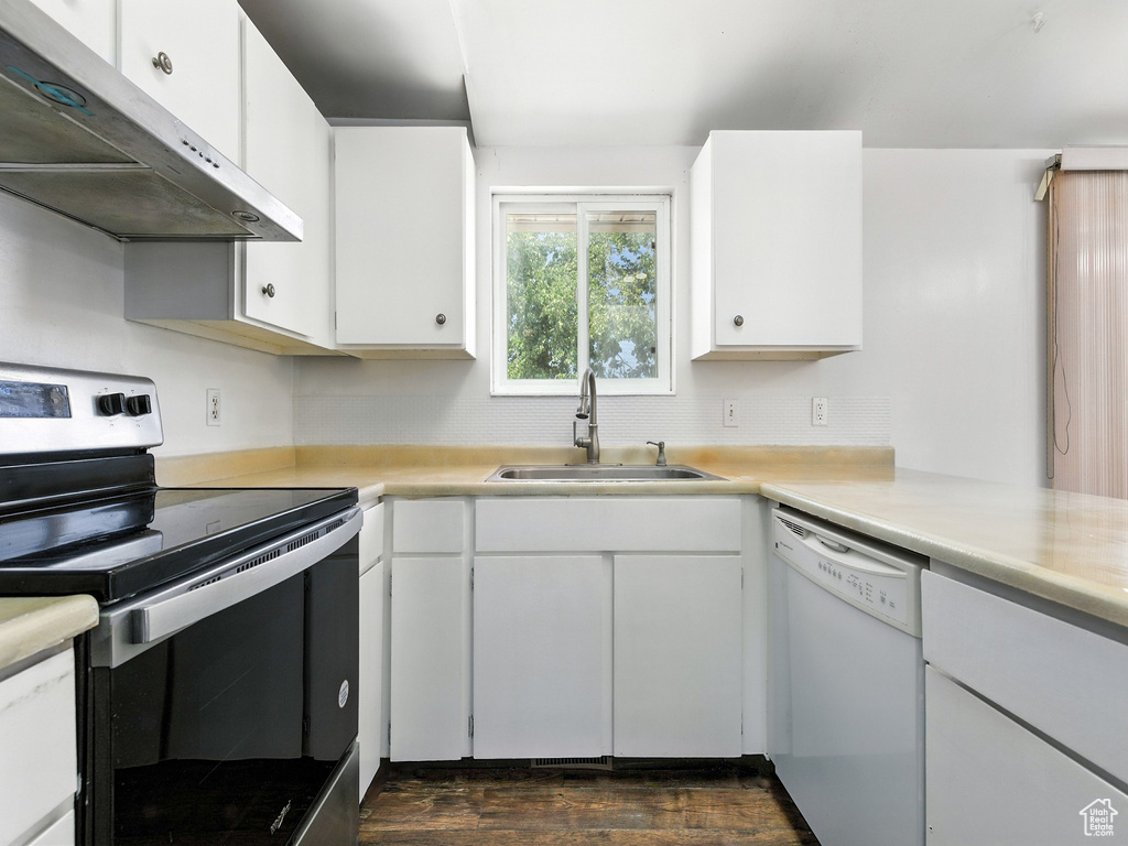 Kitchen with stainless steel electric stove, range hood, white dishwasher, and light countertops