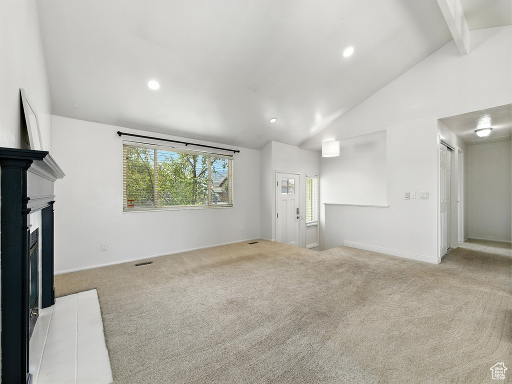 Unfurnished living room featuring carpet floors, a fireplace with flush hearth, beamed ceiling, recessed lighting, and high vaulted ceiling