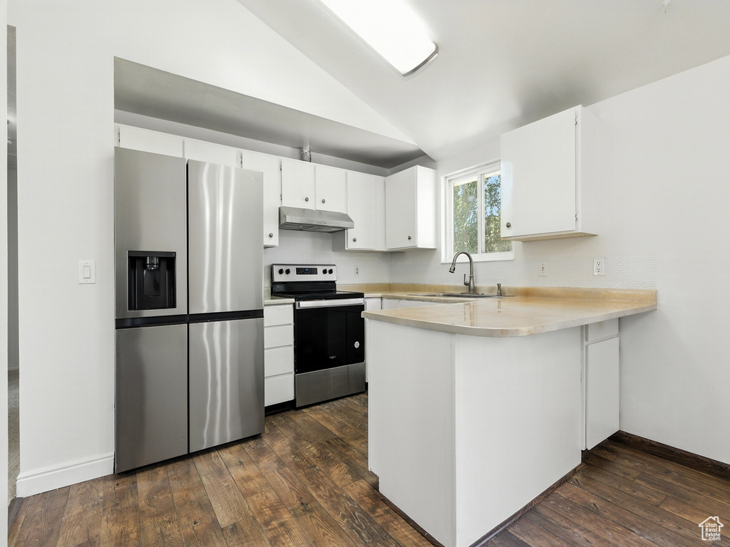 Kitchen featuring appliances with stainless steel finishes, under cabinet range hood, vaulted ceiling, a peninsula, and light countertops