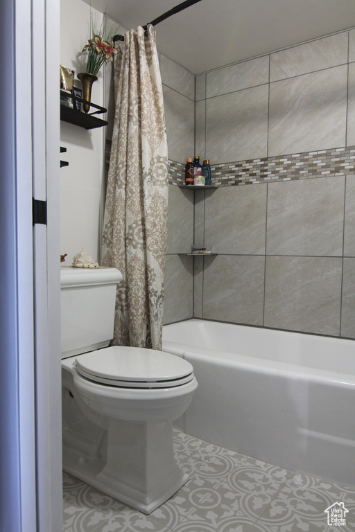 Bathroom featuring toilet and shower / tub combo with curtain