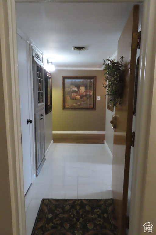 Hall featuring tile patterned floors and crown molding